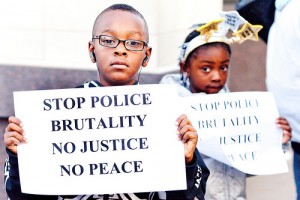 Children hold signs protesting police brutality. Photo courtesy of thefreethoughtproject.com.